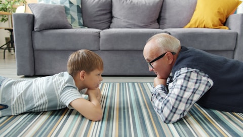 Grandfather and grandson lying on the floor talking.