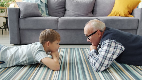 Grandfather and grandson lying on the floor talking.