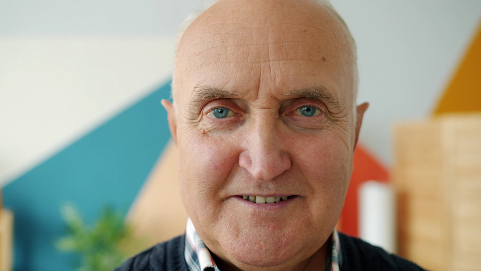 An older man smiling warmly at home