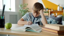 Young boy concentrating while doing homework at desk.