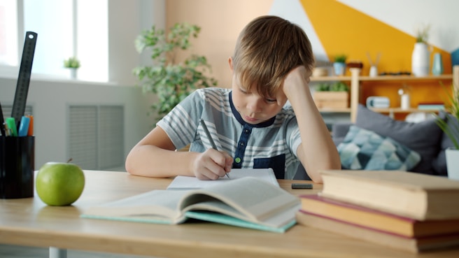 Young boy concentrating while doing homework at desk.