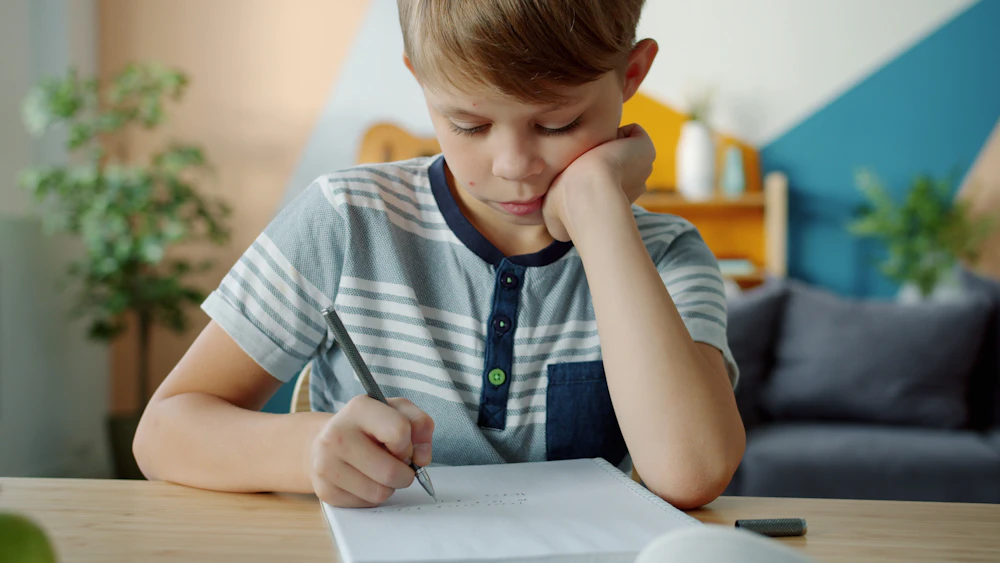 A child concentrating on homework at a desk at home.
