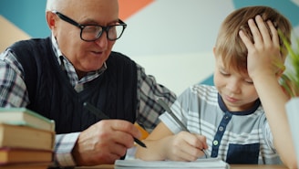 Grandfather helps grandson with homework at table