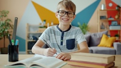 Smiling boy wearing glasses studying at a desk.