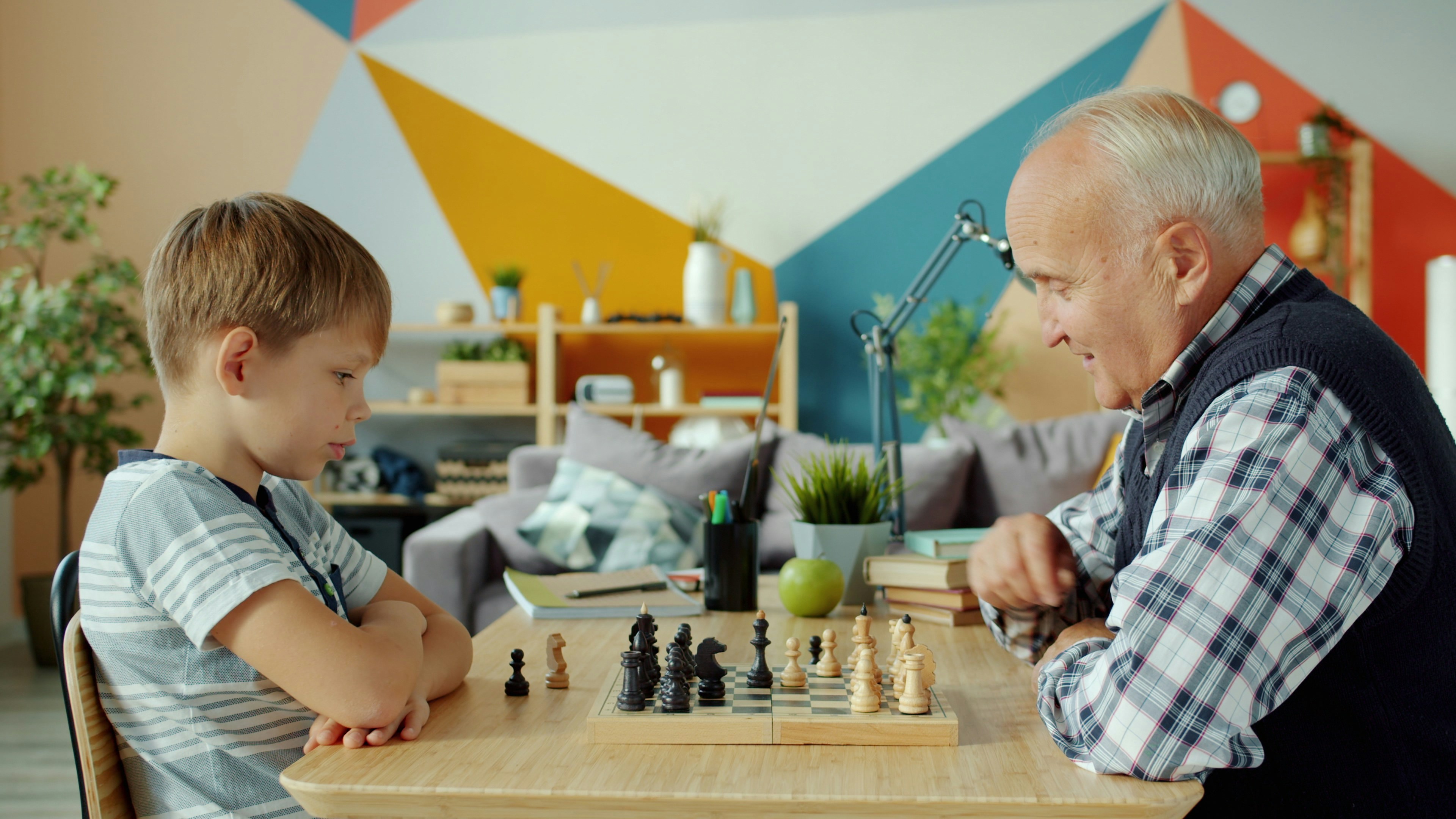 Grandfather and grandson playing chess at a table.