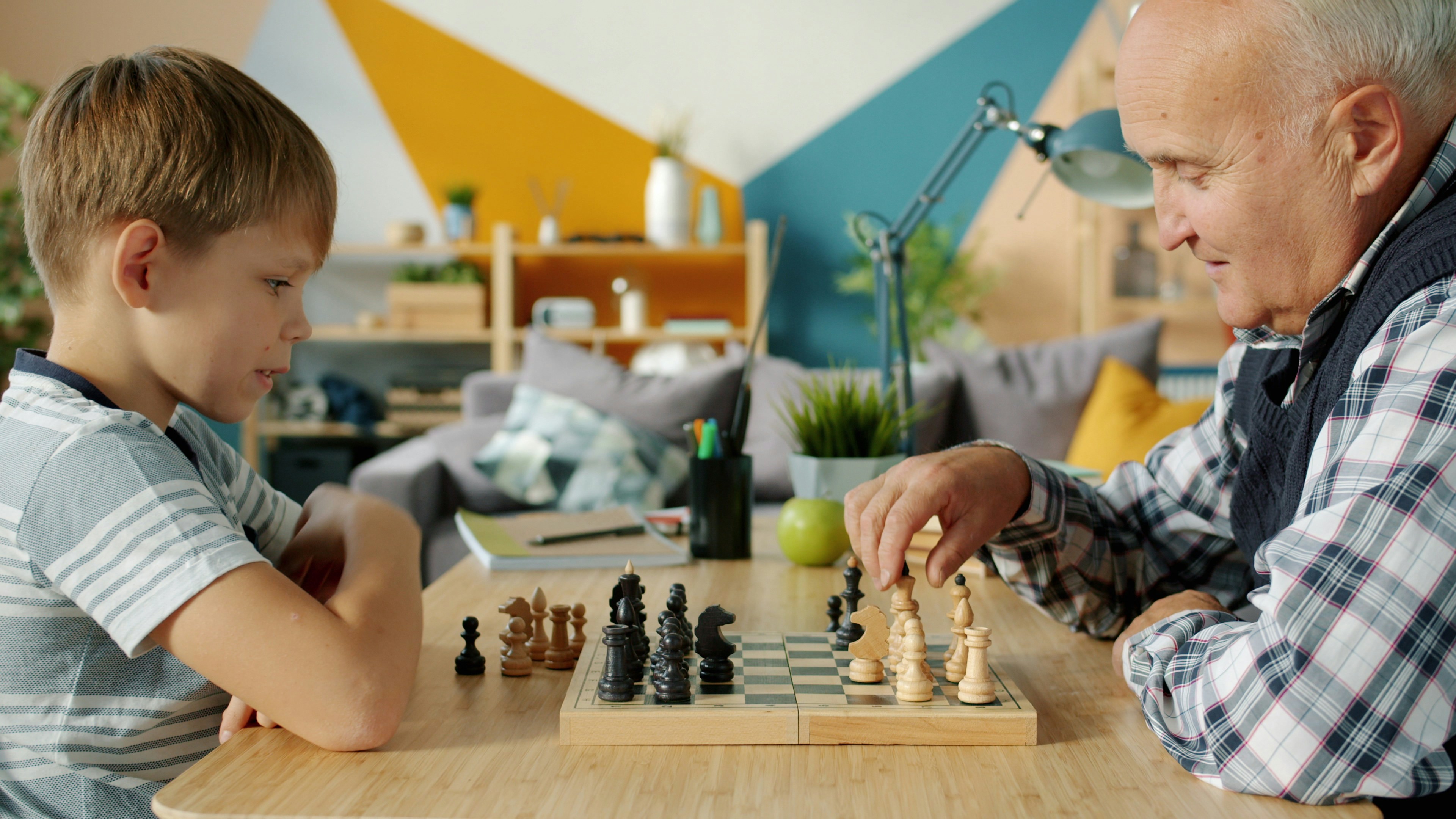 Grandfather and grandson playing chess at a table.