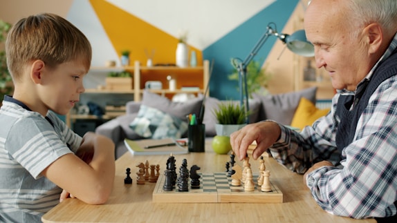 Grandfather and grandson playing chess at a table.