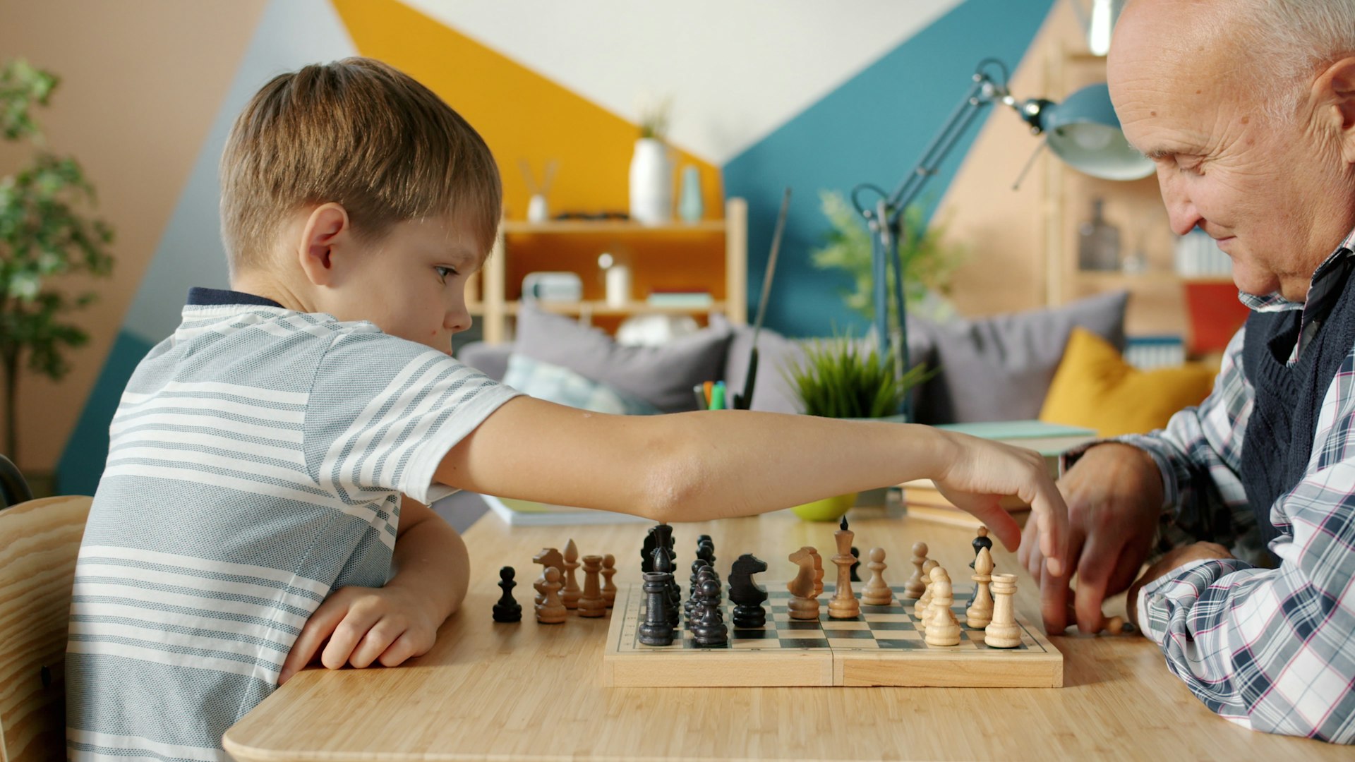 Grandfather and grandson playing chess together indoors.