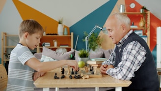 Grandfather and grandson playing chess at a table.
