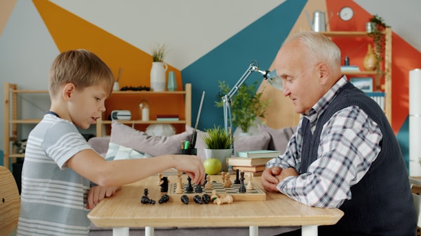 Grandfather and grandson playing chess at a table.