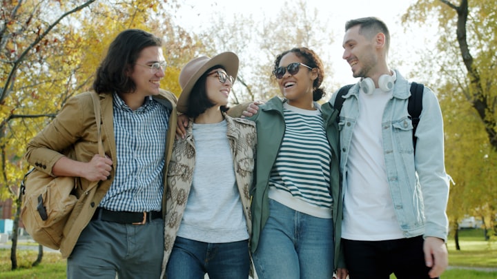Four friends walking together through a park while planning their group trip
