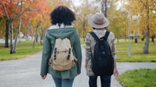 Two friends walking on a path in autumn park