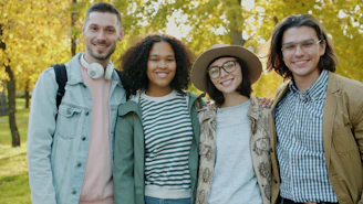 Four friends smiling in a park during autumn