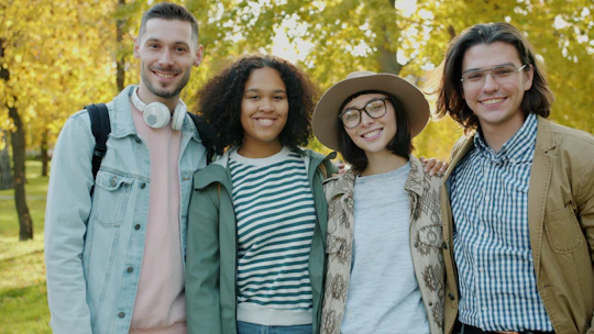 Four friends smiling in a park during autumn