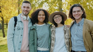 Four friends smiling in a park during autumn