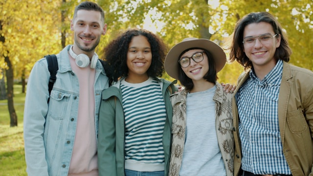 Four friends smiling in a park during autumn