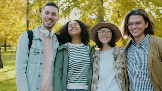 Four smiling friends posing together outdoors in autumn