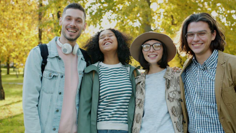 Four smiling friends posing together outdoors in autumn