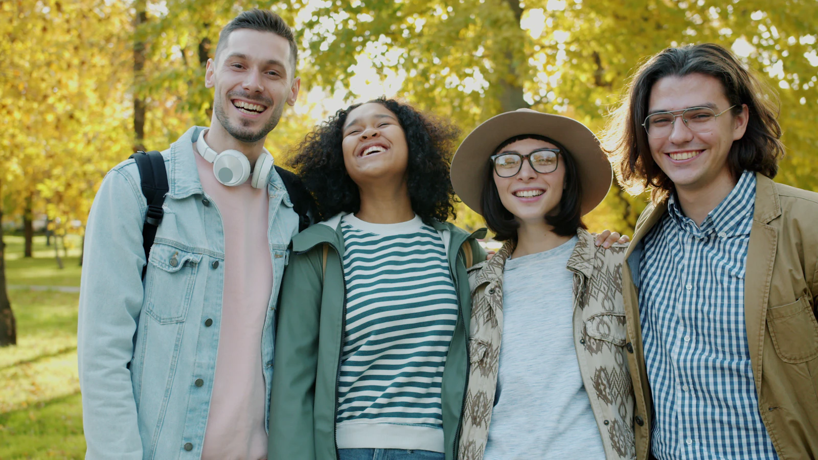 Four diverse friends posing and laughing together outdoors