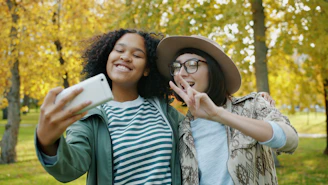 Two friends taking a selfie in an autumn park