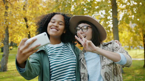 Two friends taking a selfie in an autumn park
