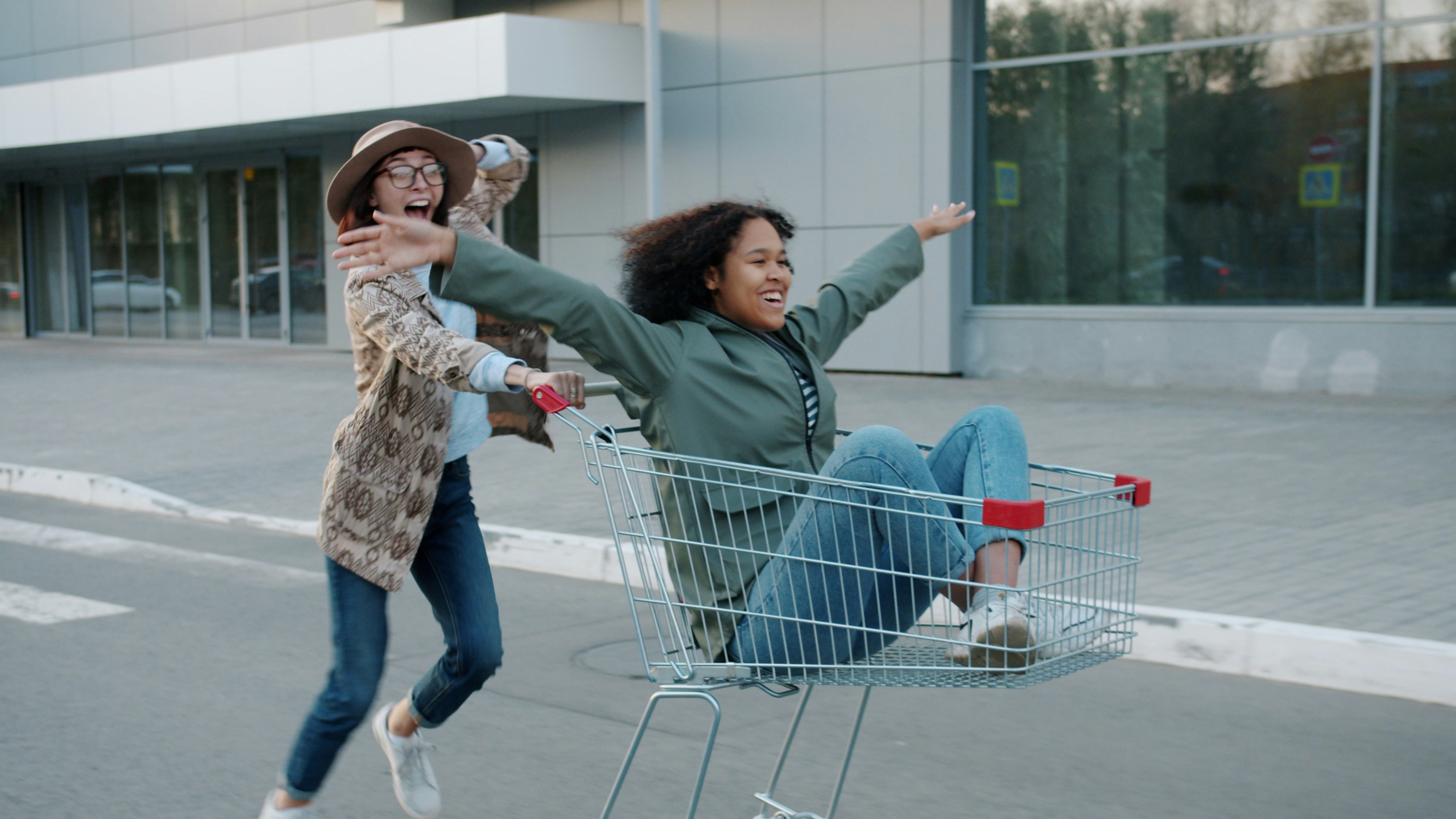 Two friends playfully riding in a shopping cart