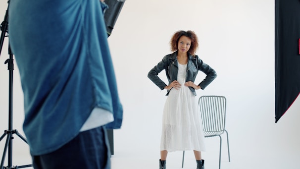 Model posing in a white dress and leather jacket.