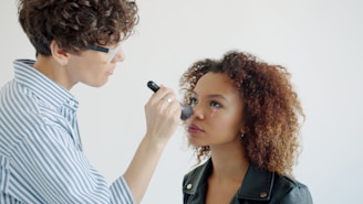 Makeup artist applying makeup to a young woman.