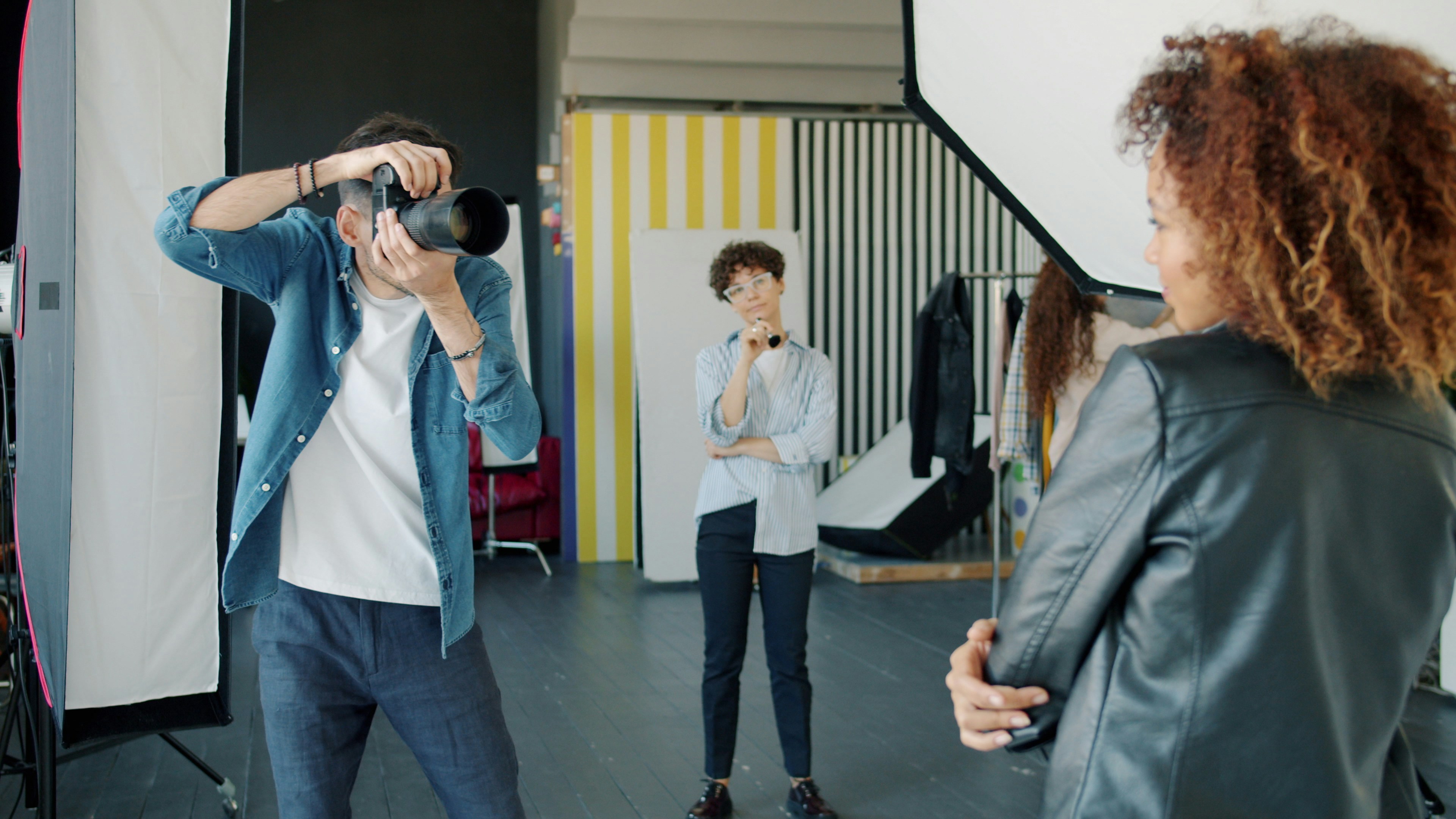 Photographer taking picture of woman in studio.