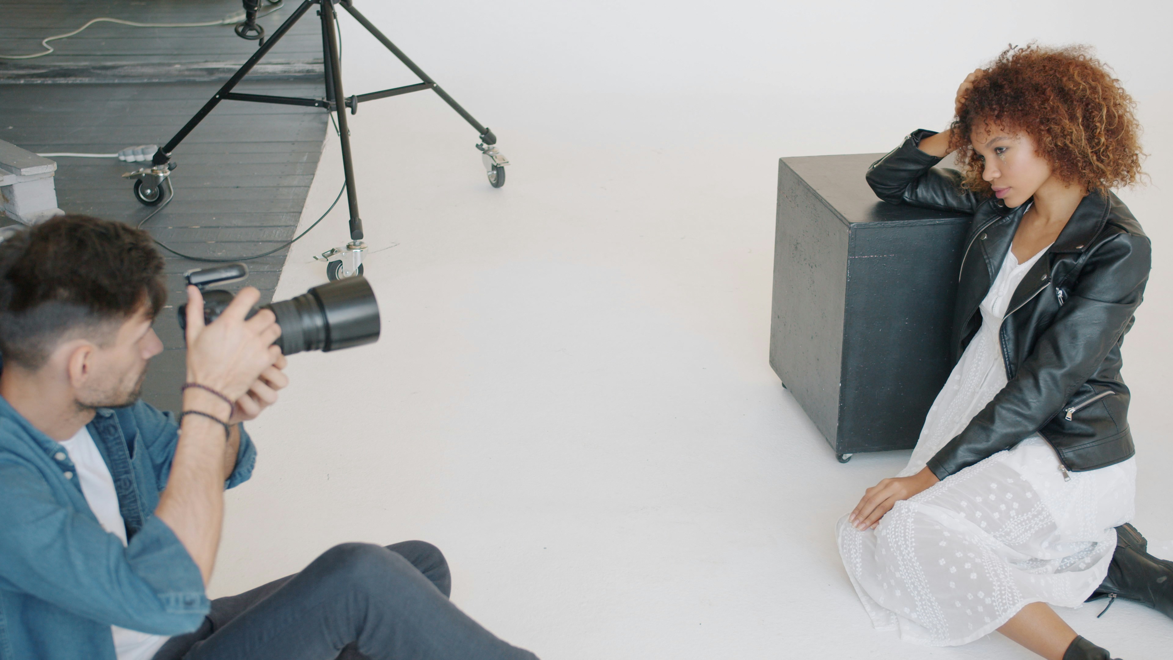 Successful male photographer is taking photo of attractive young lady in modern studio