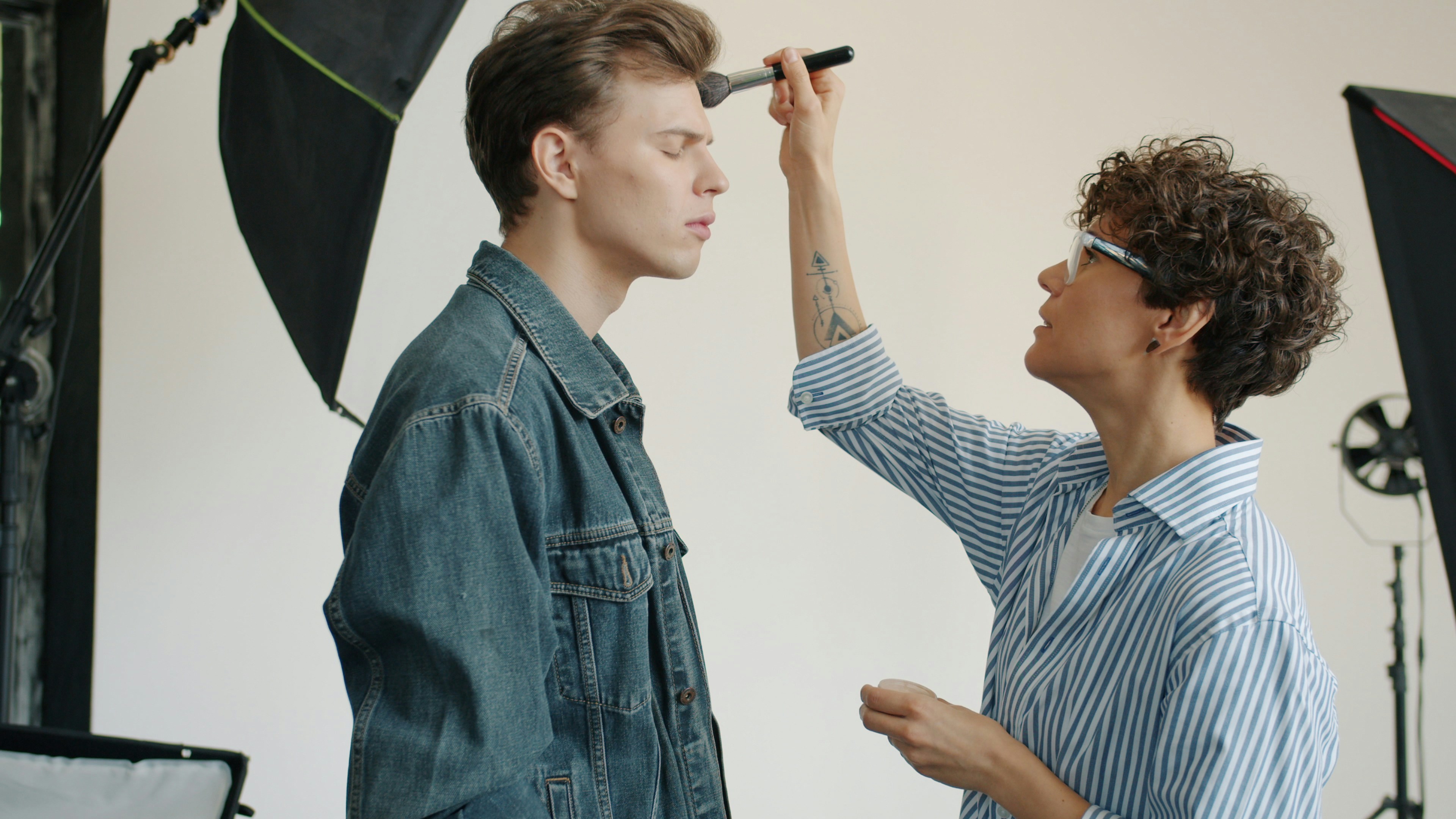 Make-up artist putting cosmetics on male model's face