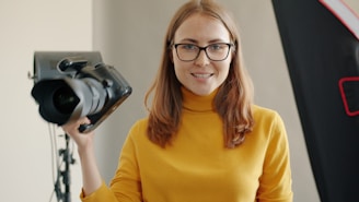 Woman holding a professional camera in a studio.