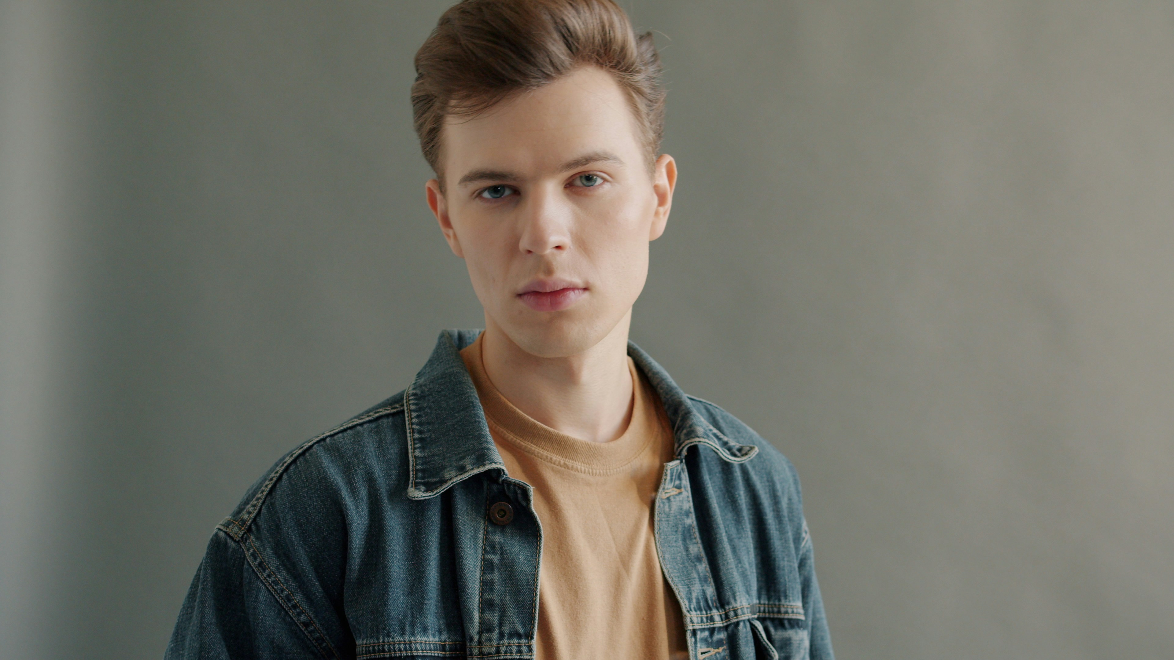 Portrait of handsome young man posing on gray background looking at camera wearing tredny garments. Modelling, attractive people and lifestyle concept.