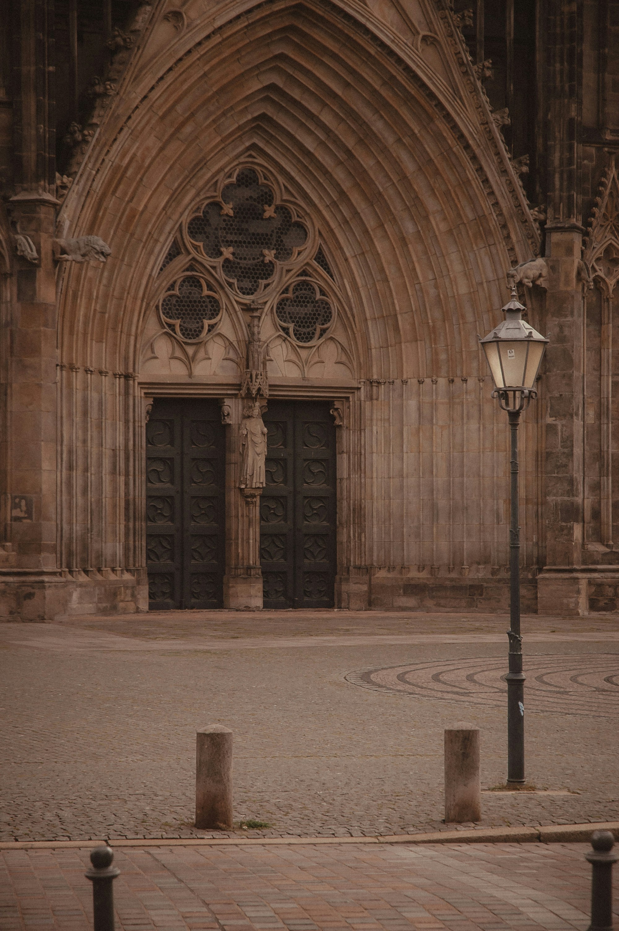Gothic cathedral entrance with ornate doors and lamp post.