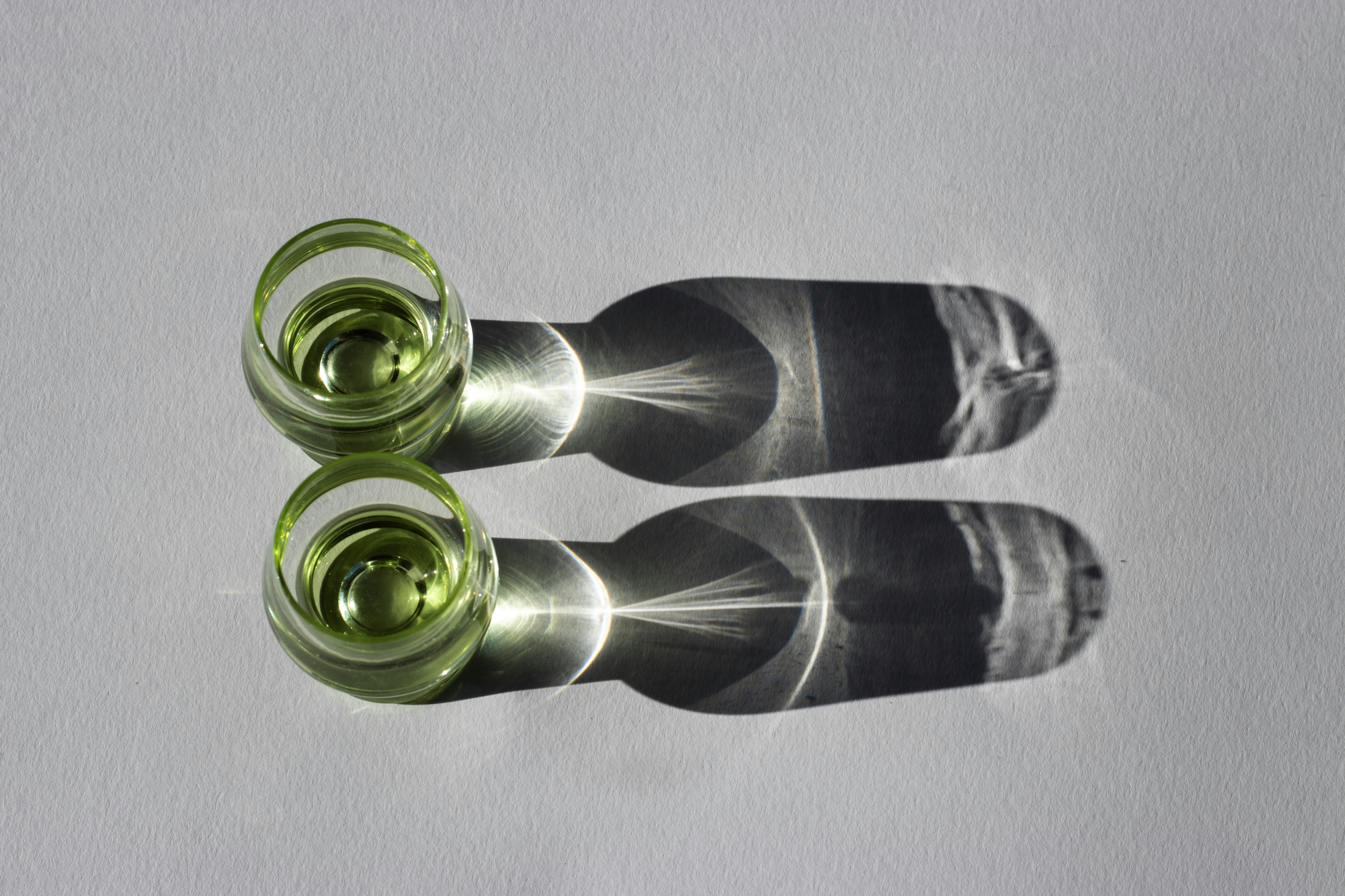 Dois copos de líquido verde com sombras dramáticas