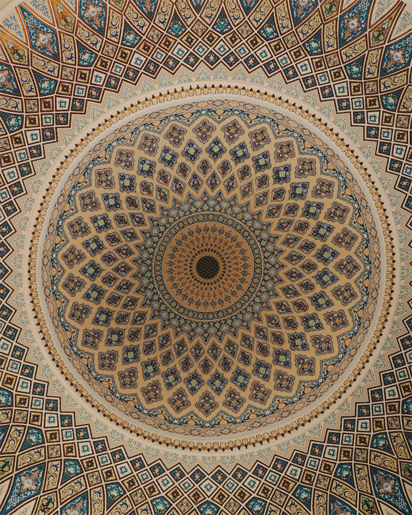 Intricate geometric patterns adorn a domed ceiling.