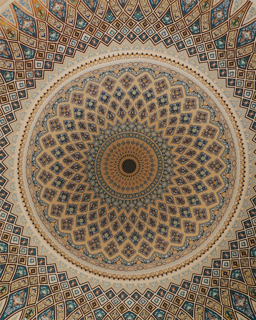 Intricate geometric patterns adorn a domed ceiling.
