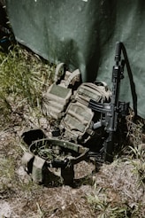 Tactical gear and rifle leaning against a wall.