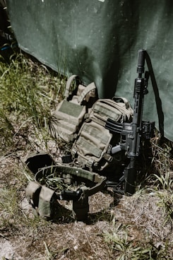 Tactical gear and rifle leaning against a wall.