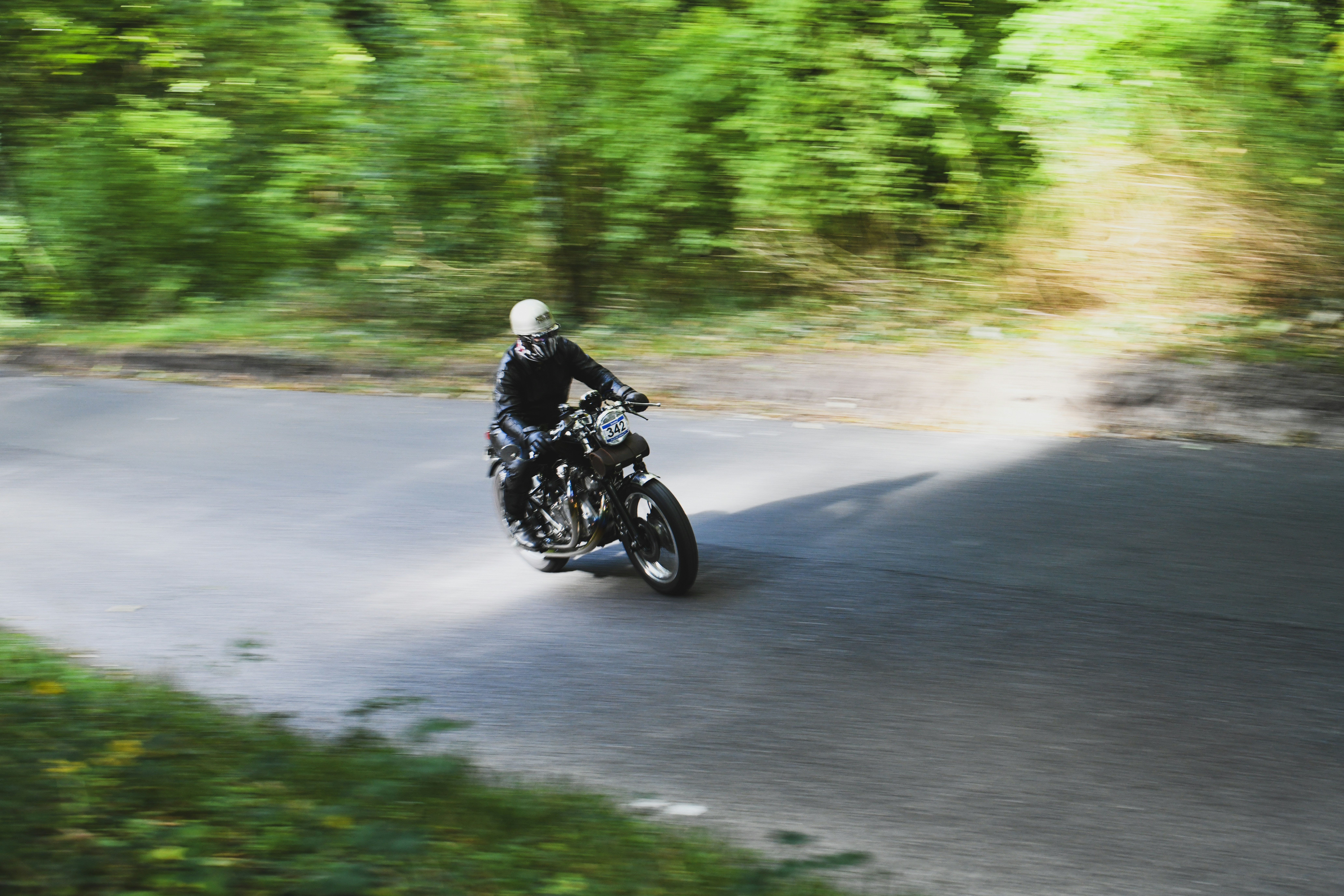 Motorcyclist riding on a winding road through trees.