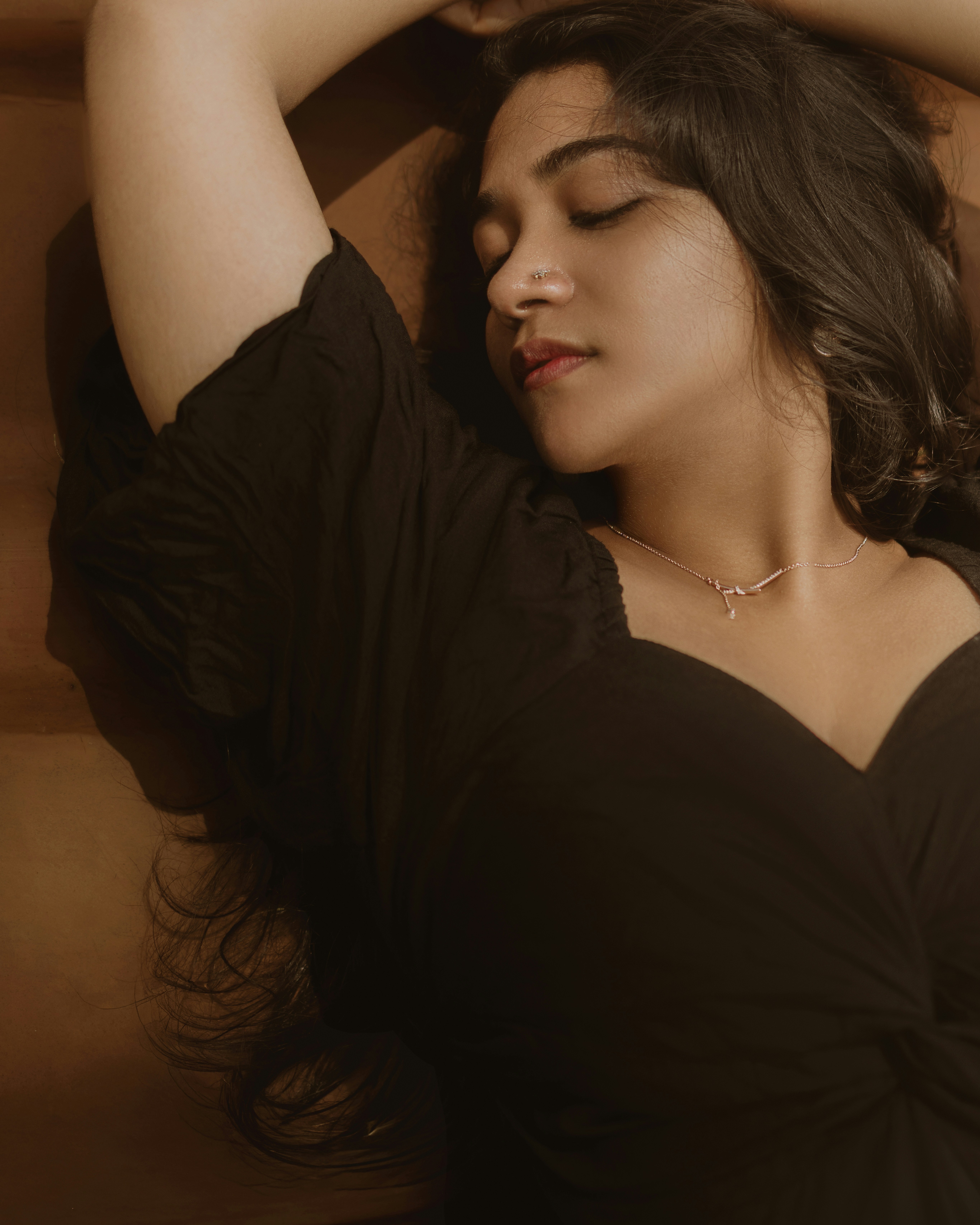 A woman in a black dress rests with eyes closed.