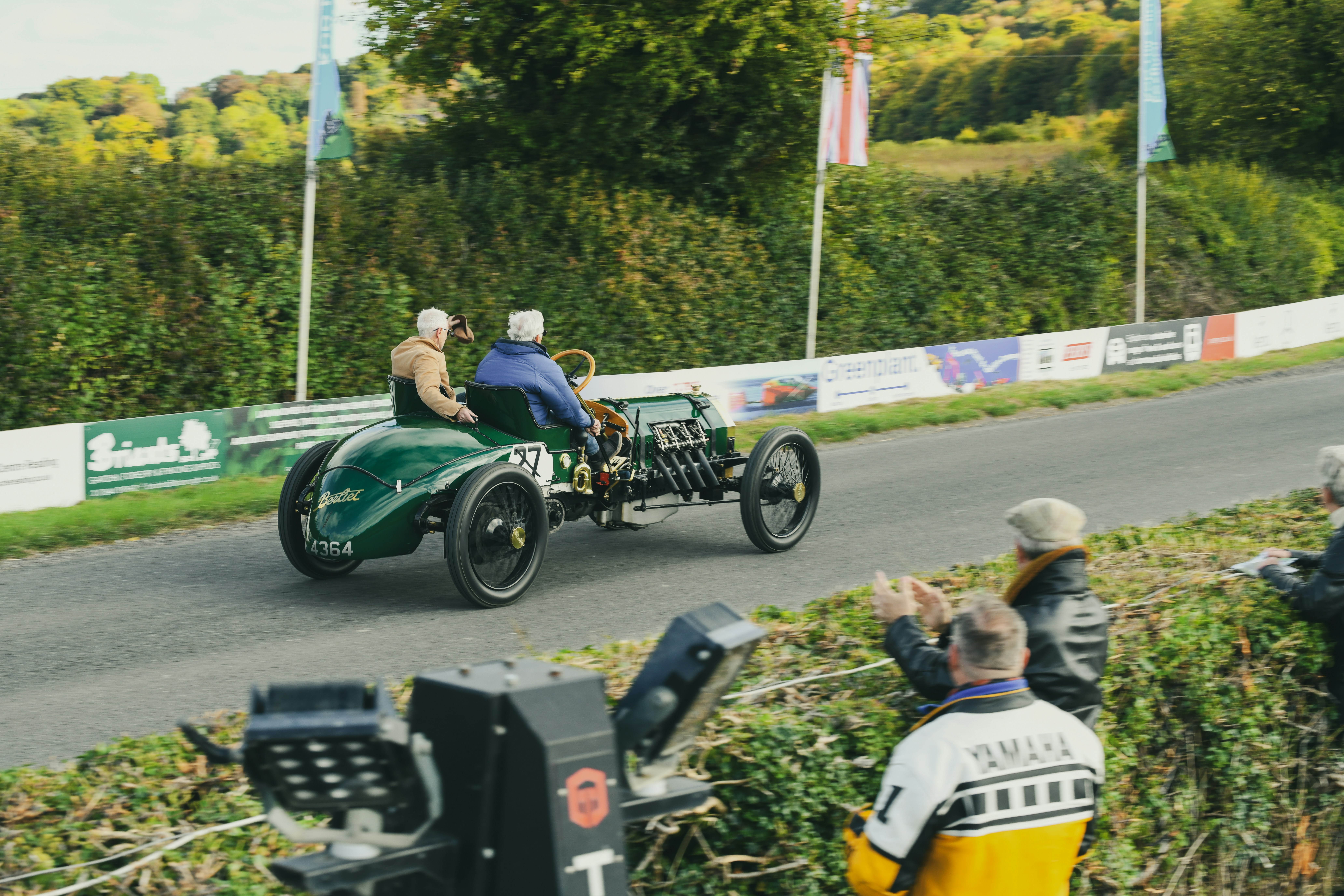 Vintage race car with two people driving on road