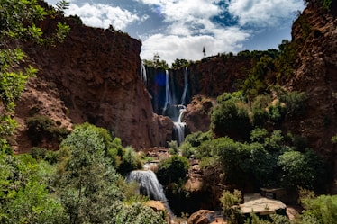 Majestic waterfalls cascade down rocky cliffs surrounded by lush greenery.