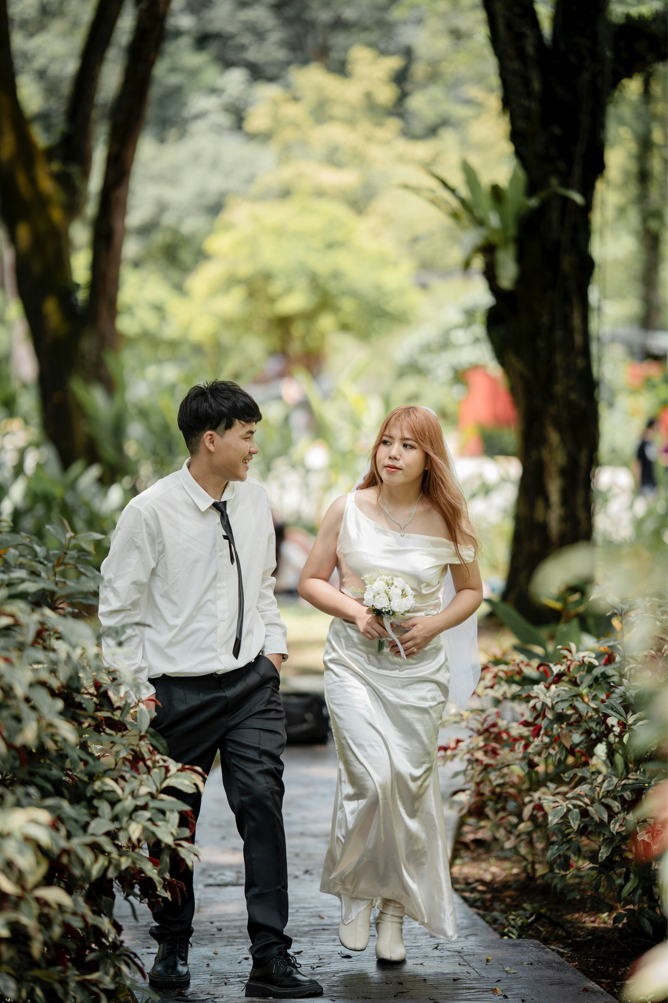 Couple walking on a path in a lush garden.