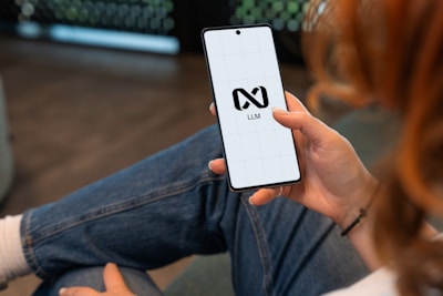 Person holding a smartphone with a logo on screen.