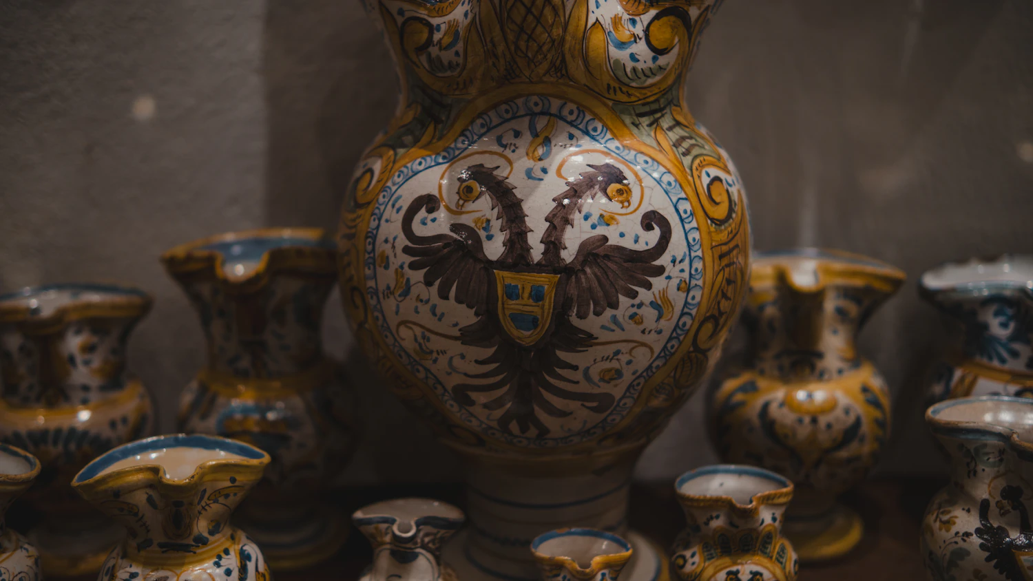 A tin-glazed earthenware jug painted with a crest in blue and ochre