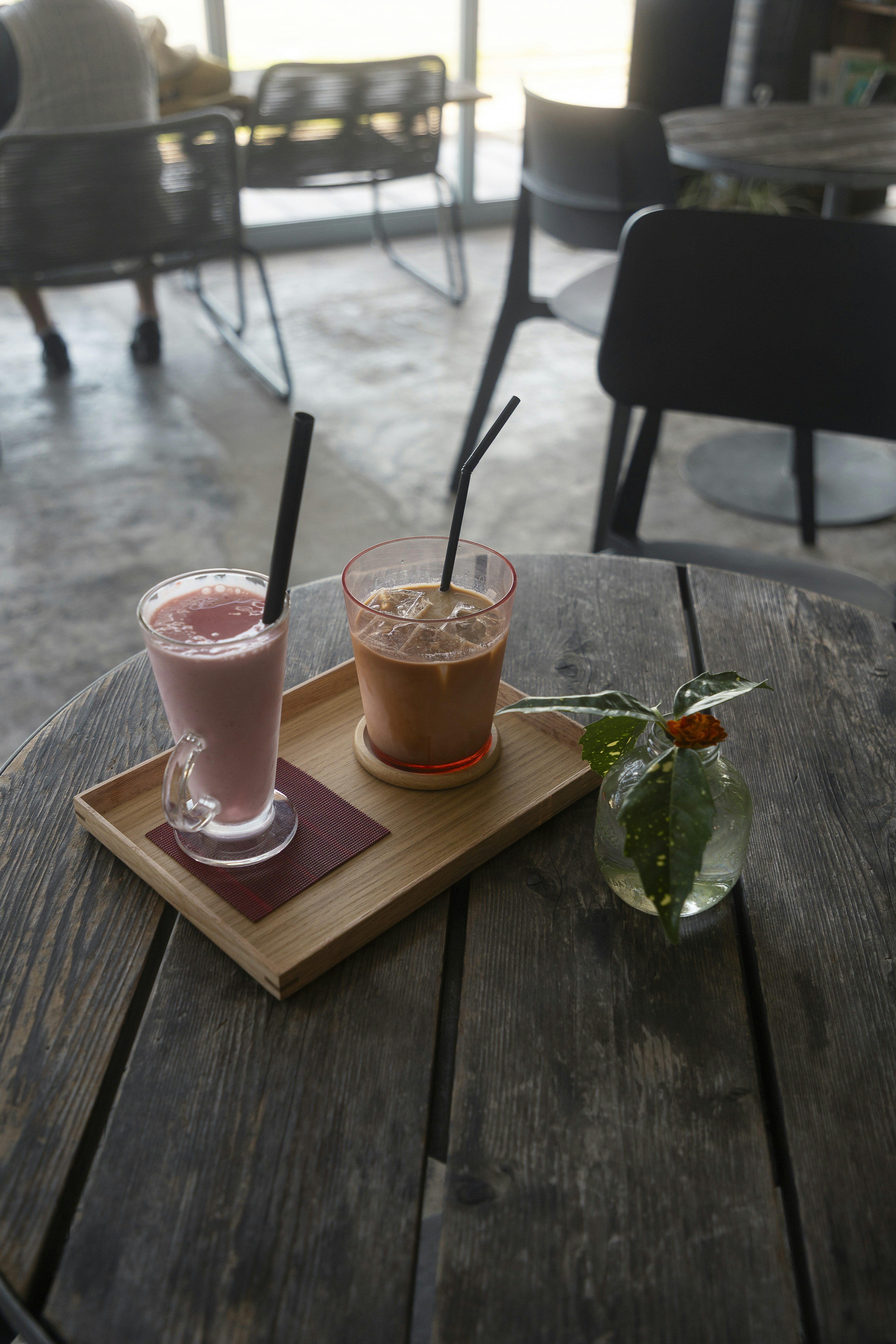 Two drinks on a wooden table with garnish.