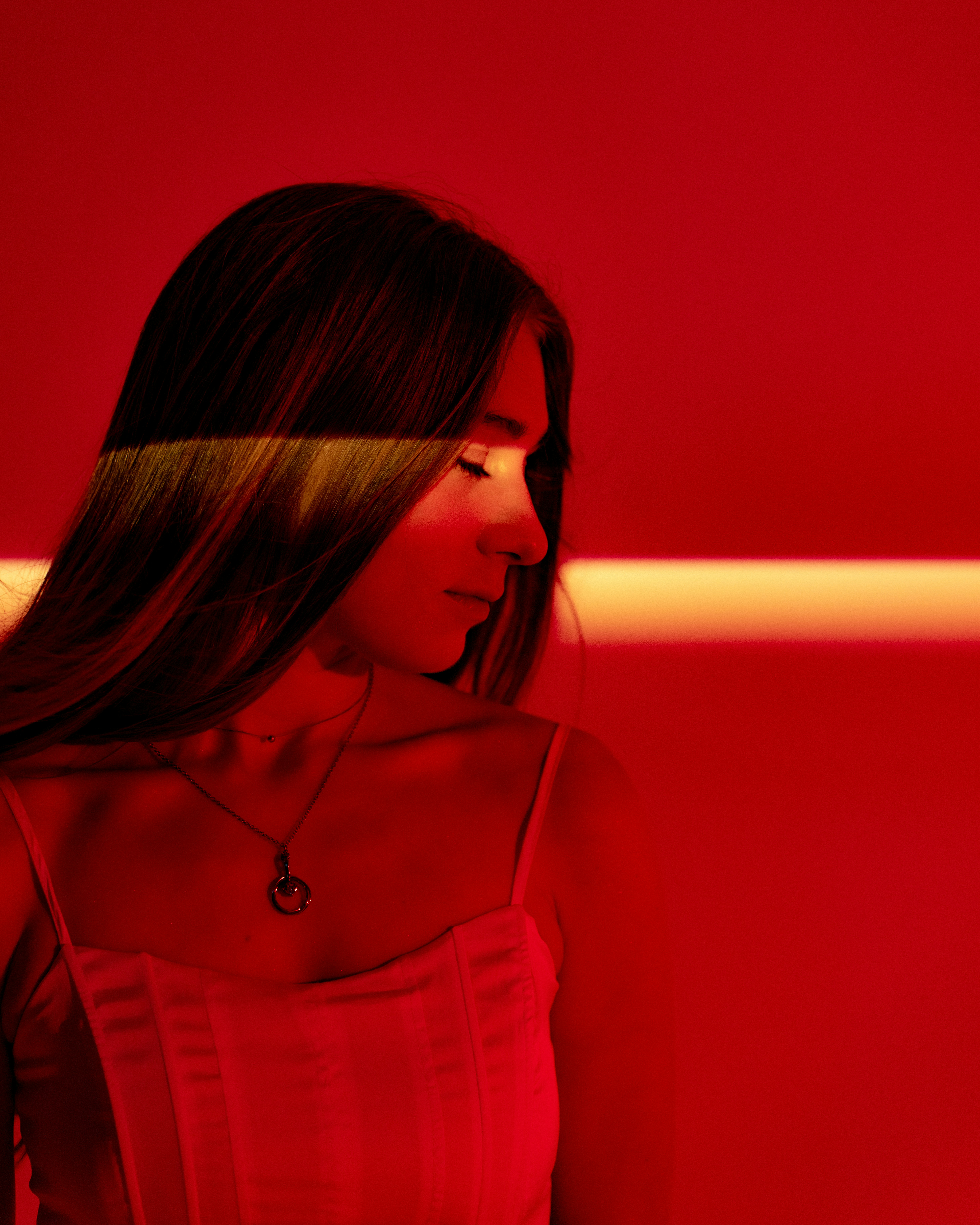 Woman with red light on face and necklace.