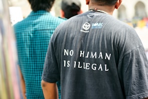 Man wearing a t-shirt with "no human is illegal" slogan.