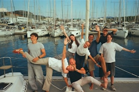 Group of friends posing on a sailboat dock.